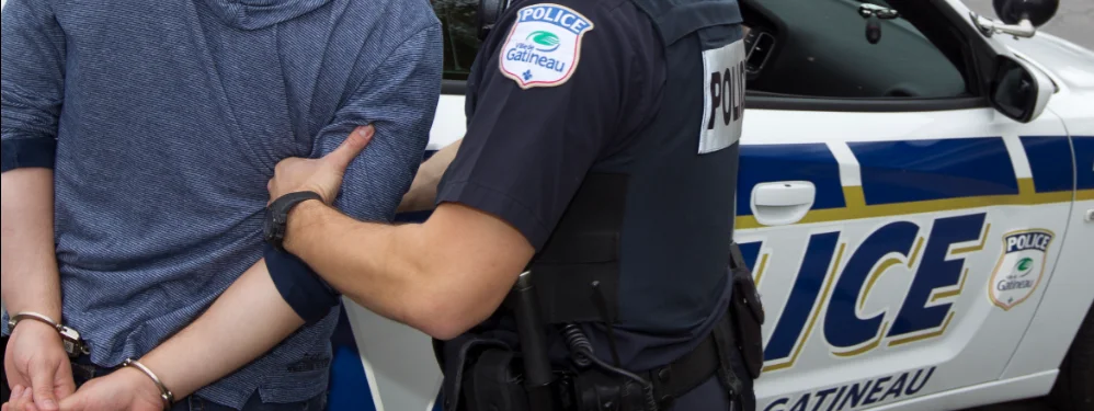 Policier qui menotte un homme près d’une autopatrouille – accusation au criminel