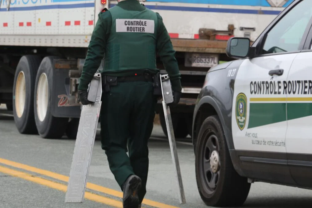 Contrôleur routier de Contrôle routier Québec qui apporte des pèse-essieux à un poids lourd – surcharge